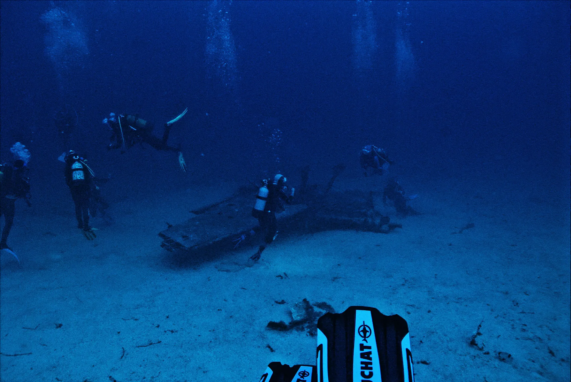 Divers exploring underwater wreckage during a deep ocean scuba dive.