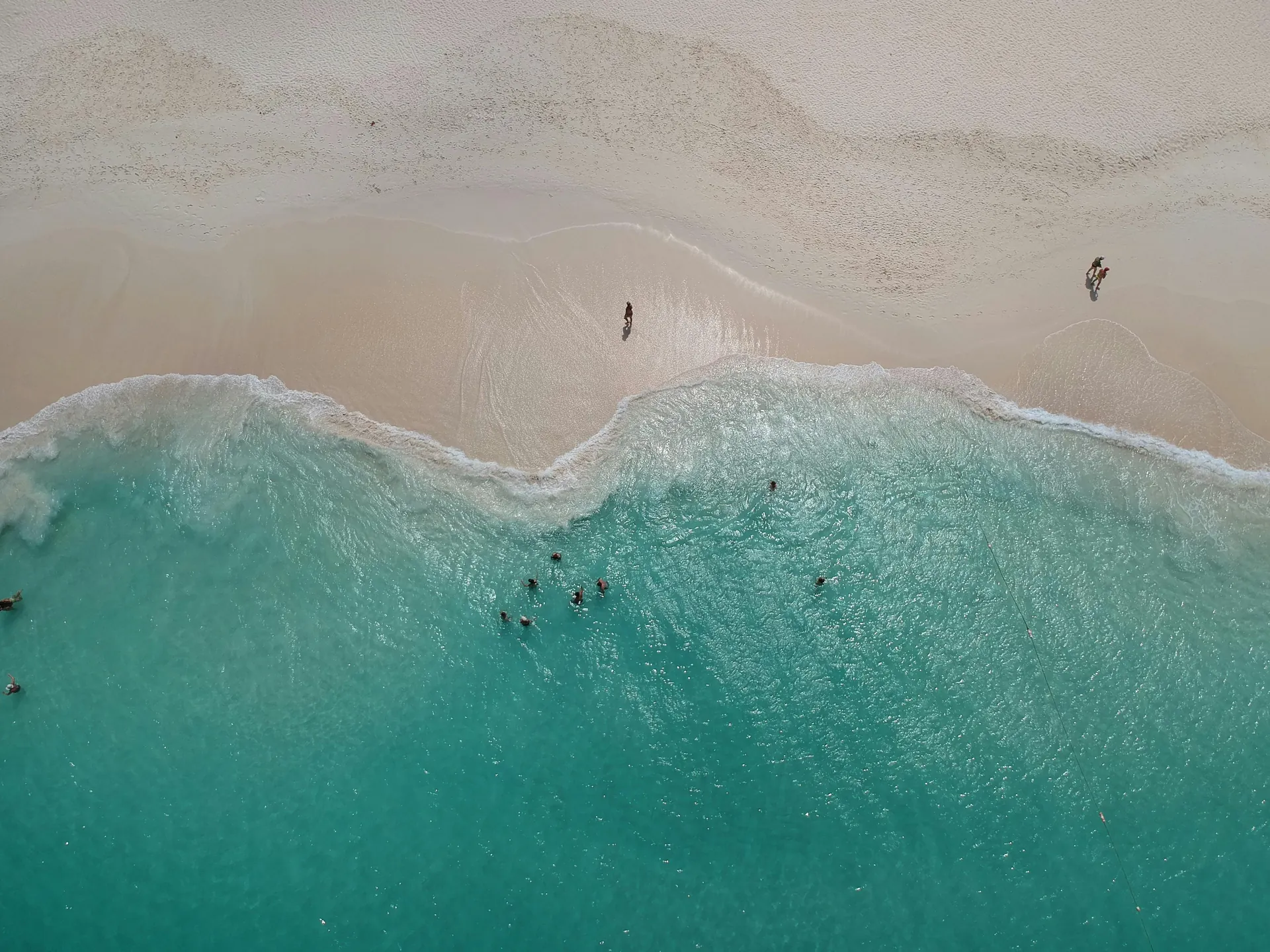 Stunning aerial view of turquoise waters meeting the sandy shore in Aruba, perfect beach escape.